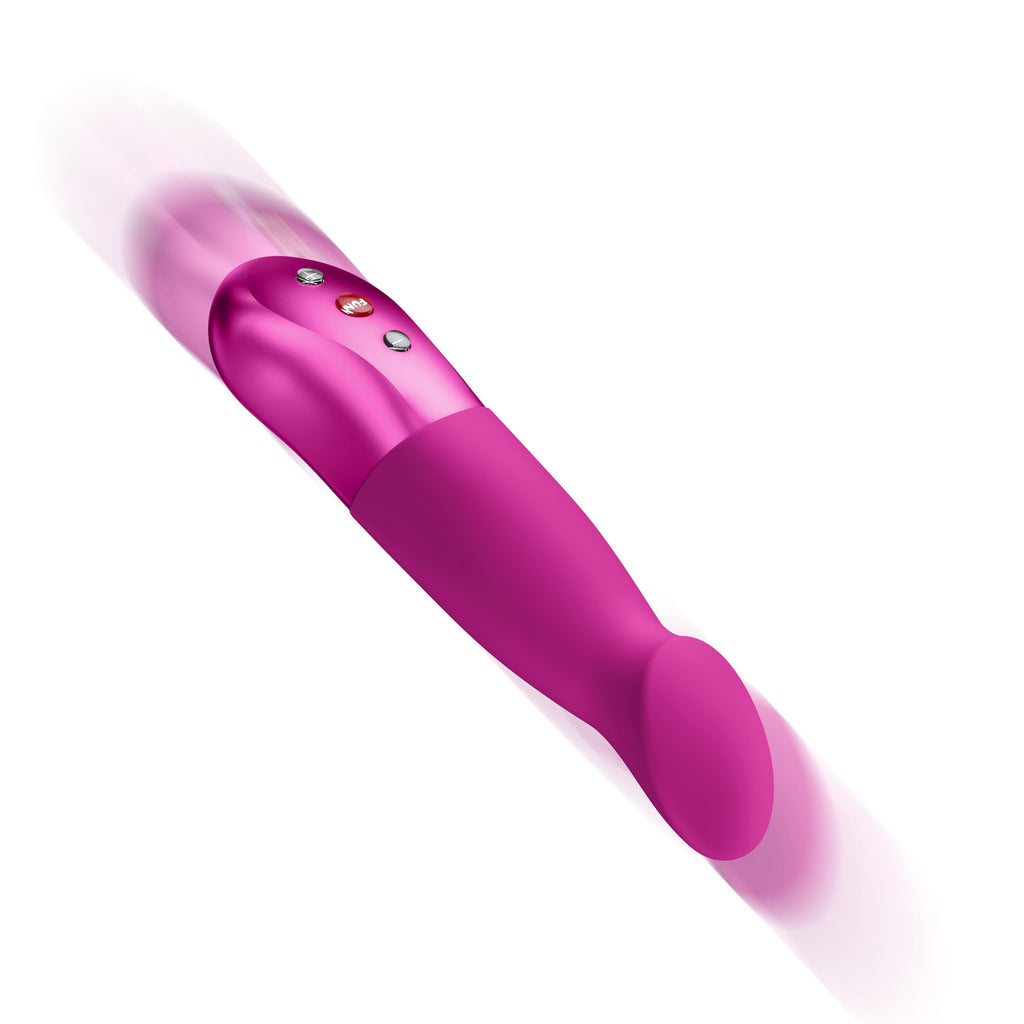 A pink handheld wand-style massager with a metallic pink handle, small control buttons, and a rounded flexible end, shown on a plain white background with motion blur at the top.